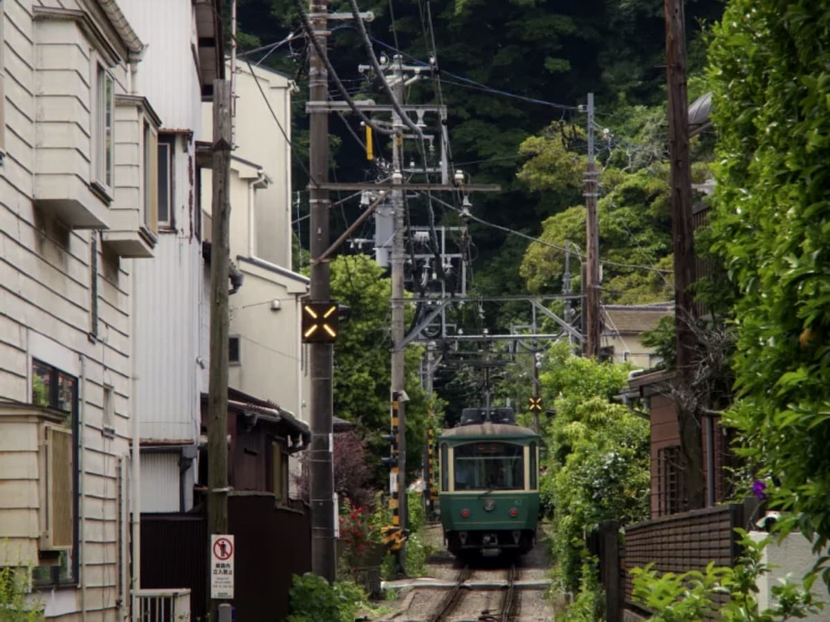 A small green train on a narrow street track, rendered through the Kodak Portra preset